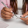 Hand placing rhinestones on a tumbler with a precision tool, crafting bling designs for tumblers.