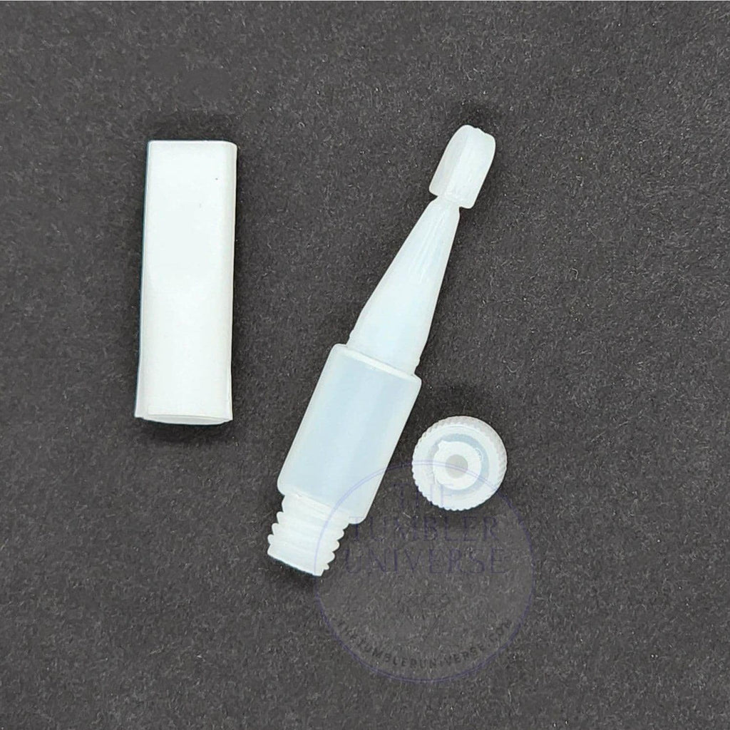 White plastic tumbler flipper tool with cap and base on dark surface