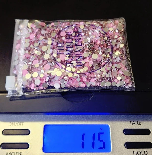 Pink and gold rhinestones in clear bag on digital scale, 115g, for tumbler bling crafting
