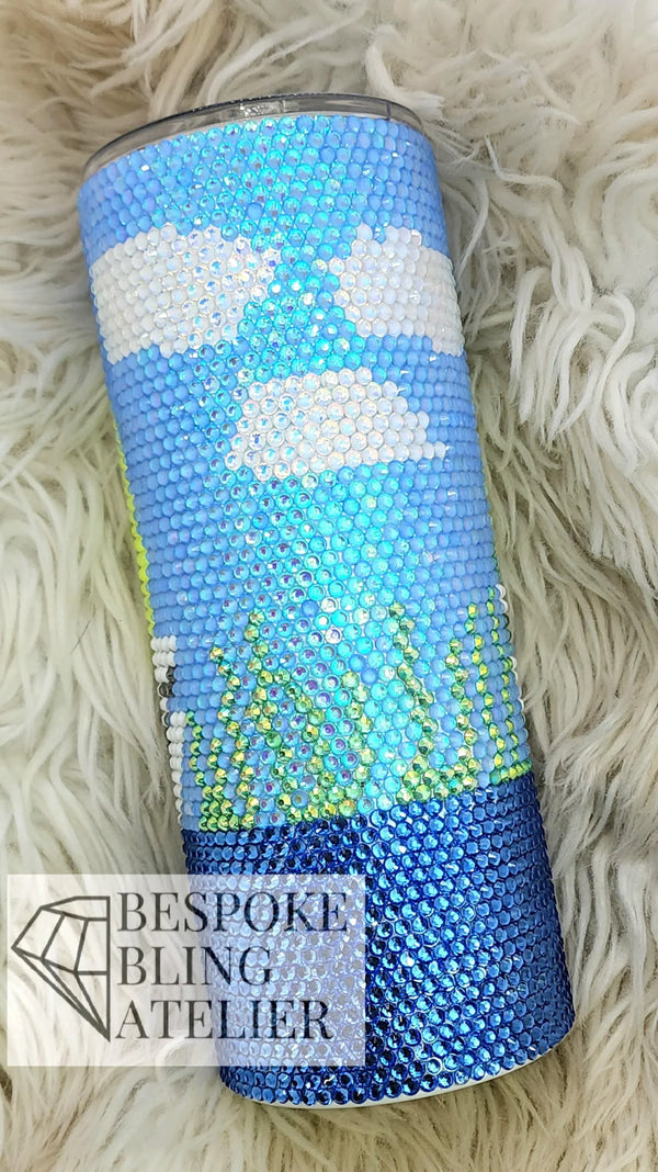 Rhinestone tumbler with blue, white, and green design on fluffy background