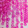 A close-up of many round pink faceted rhinestones or gems scattered across a white surface, with a faint 'The Tumbler Universe' watermark over the center.