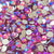 A close-up pile of round, faceted rhinestones with an iridescent pink, purple, and blue finish, showing their silver-toned metal backs. One rhinestone in the center has a visible brand stamp reading the tumbler universe