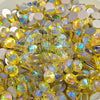 A close-up pile of round faceted rhinestones with a yellow-gold iridescent finish, showing rainbow reflections